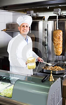 Man cook making kebab dish on kitchen in fast food restaurant