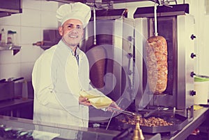 Man cook making kebab dish on kitchen in fast food restaurant