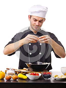 A large young guy, the chef, breaks the egg into a black plate.