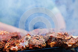 Man is cooking BBQ Roasted Pork Meat On The Hot Charcoal Grill With Smoke.