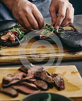 Man cooking burgers grilled meat wooden board close up