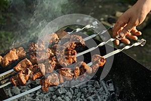 Man cooking delicious meat on brazier outdoors, closeup