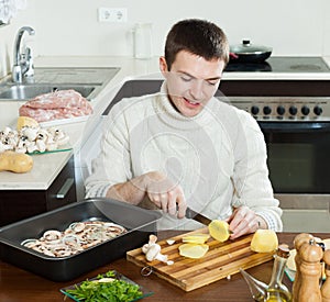 Man Cooking french-style veal- cutting potatoes