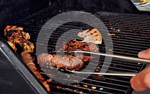 A man cooking grilled barbecues on fire outdoors