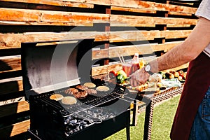 Man cooking grilled meat burgers for outdoors barbecue