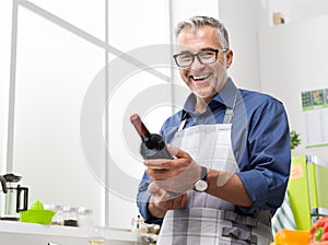 Man cooking and holding a wine bottle