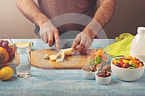 Man cooking at home preparing fruit salad