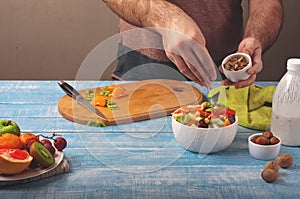 Man cooking at home preparing fruit salad