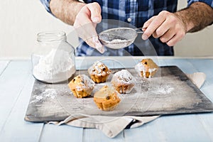 Man cooking homemade cupcakes with raisins and powdered sugar