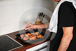 man cooking marinated chicken at home