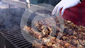 Man cooking meat on barbecue grill for his friends at summer outdoor party. Cooking pork meat on hot charcoal. Closeup