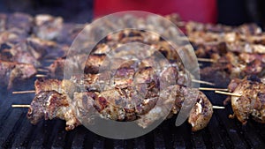 Man cooking meat on barbecue grill for his friends at summer outdoor party. Cooking pork meat on hot charcoal. Closeup