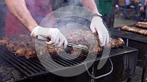 Man cooking meat on barbecue grill for his friends at summer outdoor party. Cooking pork meat on hot charcoal. Closeup