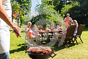 Man cooking meat on barbecue grill at summer party