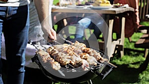 Man cooking meat on barbecue grill at summer party