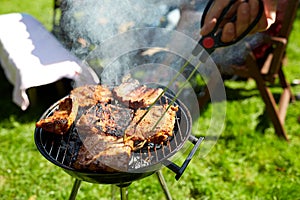 Man cooking meat on barbecue grill at summer party