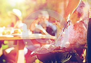 Man cooking meat on barbecue grill at summer party