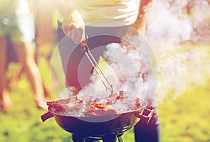 Man cooking meat on barbecue grill at summer party