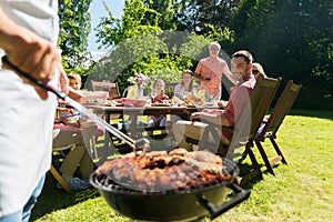 Man cooking meat on barbecue grill at summer party