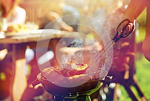 Man cooking meat on barbecue grill at summer party