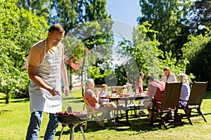 Man cooking meat on barbecue grill at summer party