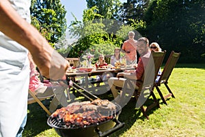 Man cooking meat on barbecue grill at summer party