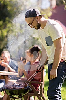 Man cooking meat on barbecue grill at summer party