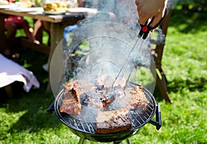 Man cooking meat on barbecue grill at summer party