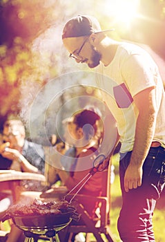 Man cooking meat on barbecue grill at summer party