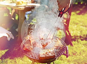 Man cooking meat on barbecue grill at summer party