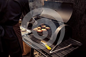 Man cooking meat for cheeseburger on grill