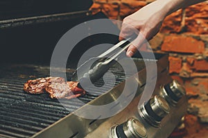 Man cooking meat steaks on professional grill outdoors