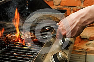 Man cooking meat steaks on professional grill outdoors