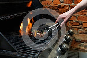 Man cooking meat steaks on professional grill outdoors