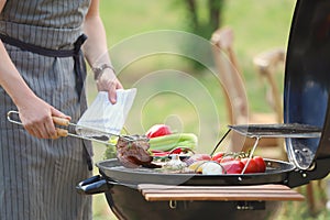 Man cooking meat and vegetables on barbecue grill outdoors