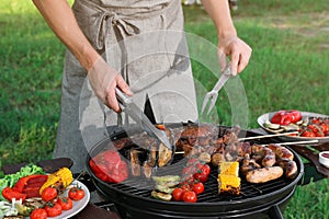 Man cooking meat and vegetables on barbecue grill outdoors, closeup