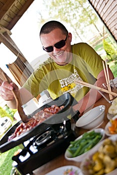 Man cooking outdoors Asian style food, korean meat on the portable stove