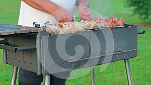 Man is Cooking Pork Barbecue Outdoors