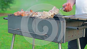 Man is Cooking Pork Barbecue Outdoors
