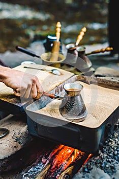 Man is cooking Turkish coffee in the box with sand under live coals