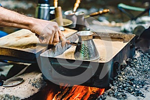 Man is cooking Turkish coffee in the box with sand under live coals