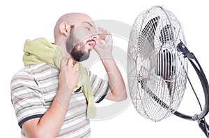 Man cooling his head with cold water bottle and fan