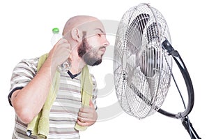 Man cooling his neck with cold water bottle and fan