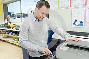Man copying paper from photocopier sunlight from window