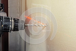 Man with cordless hand drill drilling a hole in concrete with laser level