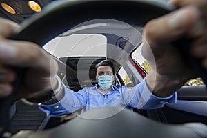 Man with corona mask driving car photographed behind the wheel