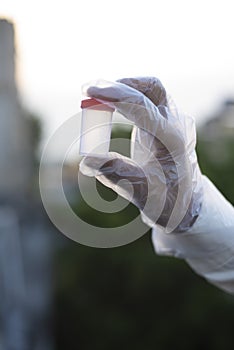 Man with corona preventive hand gloves holding a medicine ampul or vaccine on rooftop outdoor.  Lock down and Home isolation