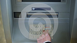Man correcting pin code on ATM keyboard, transfer funds between bank accounts