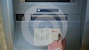 Man correcting pin code on ATM keyboard, transfer funds between bank accounts