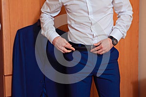 Man corrects belt, fees groom, man's hands, dressing, man wear pants, jeans, man's style